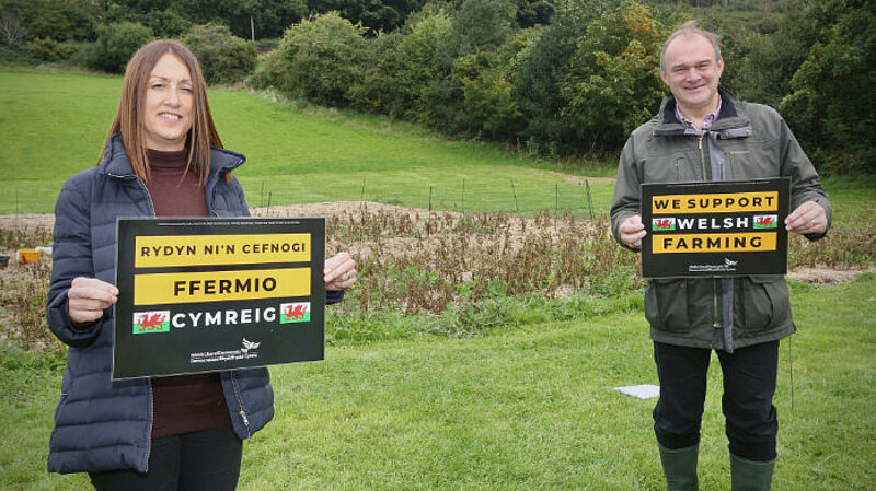 [Translate to Welsh:] Welsh Lib Dem Leader Jane Dodds and UK Leader Ed Davey holding signs saying "Back Welsh Farming"